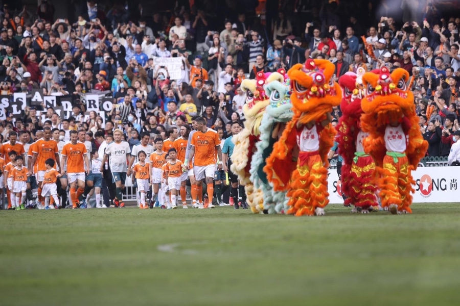 the football players entering the field with lion dance team