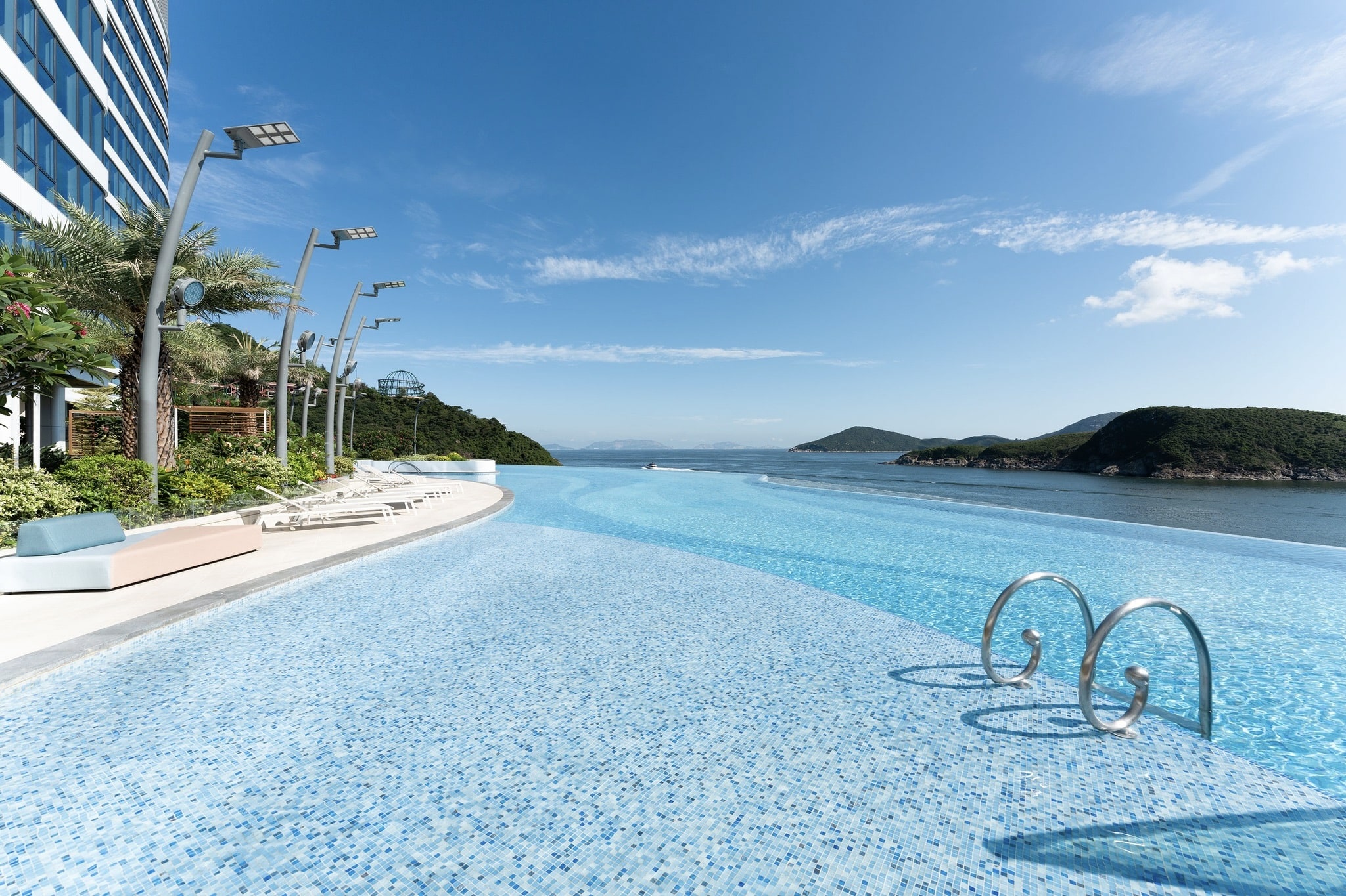The infinity pool at the Fullerton Ocean Park gives overlooks the Abderdeen Channel. On the left, there are deck chairs and on the right are islands.