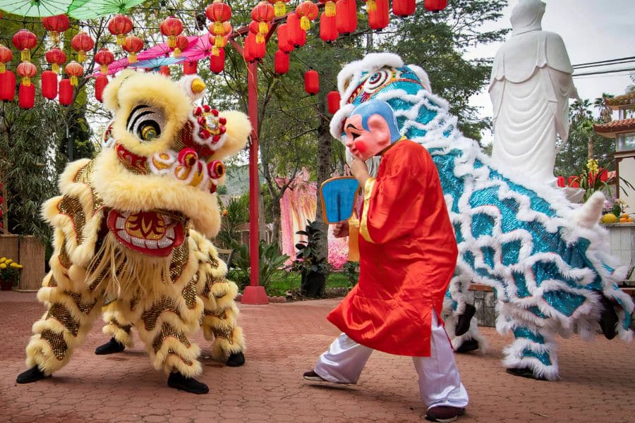 A Buddhist monk character playing with and leading the lion in a lion dance show